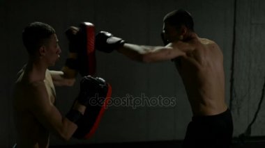 Ağır çekim genç savaşçıların Tay pedleri kullanarak kick boks maçı için spor salonunda eğitim