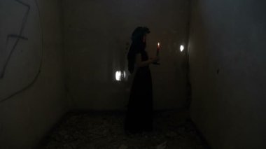 Şeytani Gotik kötü kadın bir mum tutan ve öfkeyle terk edilmiş karanlık bir odada çığlık etrafında dönme