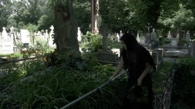 Cenaze kadın dul bir taç moss Ivy ve dizlerinin ağlıyor yabani ot kaplı heykeli ile eski mezarı üzerine yerleştirerek boyalı