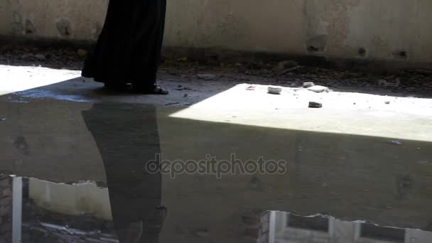 Gothic girl with long hair captive in a haunted house standing near a ruined window looking outside — Stock Video