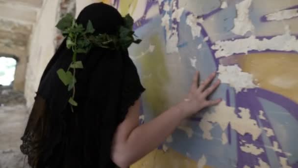Жуткая готическая девушка, прикасающаяся и слушающая стену в разрушенной комнате в поисках призраков — стоковое видео