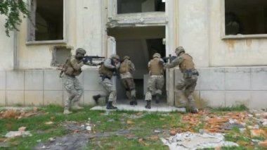Kamufle askerler terk edilmiş bir binada silahlarla operasyonel bir egzersiz sırasında yürüyüş.