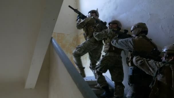 Солдаты на миссии по уничтожению лидера террористов, поднимающегося на первый этаж заброшенного здания в поисках цели — стоковое видео