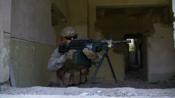 Movimiento lento de soldado armado en camuflaje con ametralladora mirando por la ventana — Vídeos de Stock