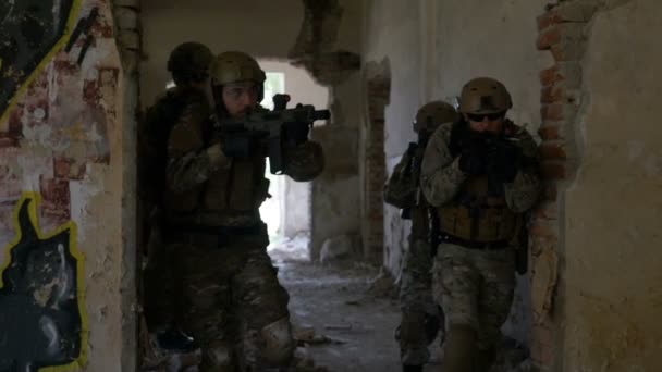 Grupo de soldados que se deslocam rapidamente através de edifícios arruinados em operação de busca e salvamento — Vídeo de Stock