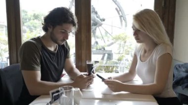 Genç çift Restoran masada oturan akıllı telefonlar kullanarak sosyal medya ağ ilişki sorunları ile