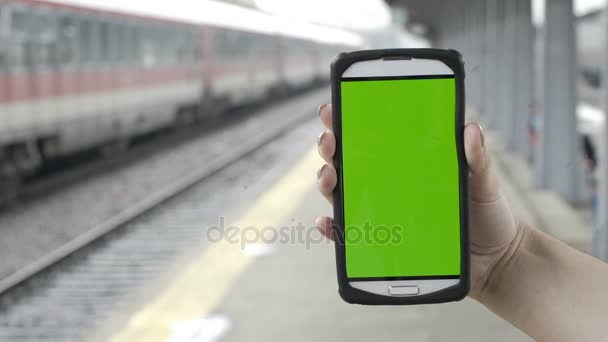 Lähikuva naisen käsissä tilalla älypuhelin vihreä ruutu chroma avain rautatieasemalla — kuvapankkivideo