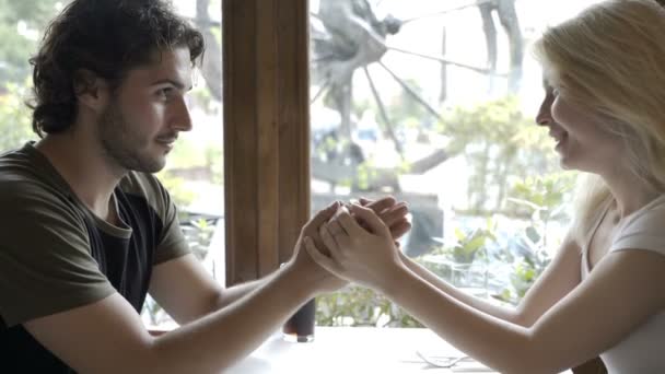 Stilig man sitter vid café bord kysser hans flickvän handen och röra vid hennes ansikte — Stockvideo