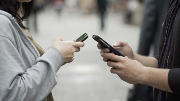 Close-up van twee tieners houden van smartphones in het openbaar plein en bladeren door sociale media netwerk — Stockvideo