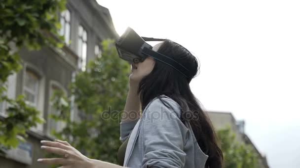 Menina muito adolescente surpreendida testando um óculos de realidade virtual ao ar livre — Vídeo de Stock