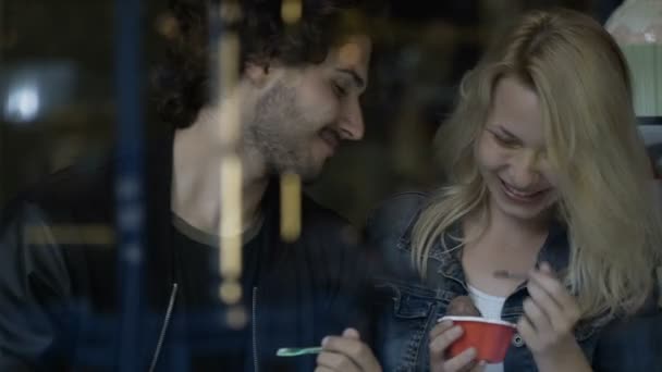 Jonge man een grap te spelen op zijn vriendin terwijl het eten van ijs in een snoep candy shop — Stockvideo