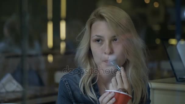 Carino giovane donna bionda mangiare gelato nel pub in attesa e sorridente alle persone che passano per strada — Video Stock