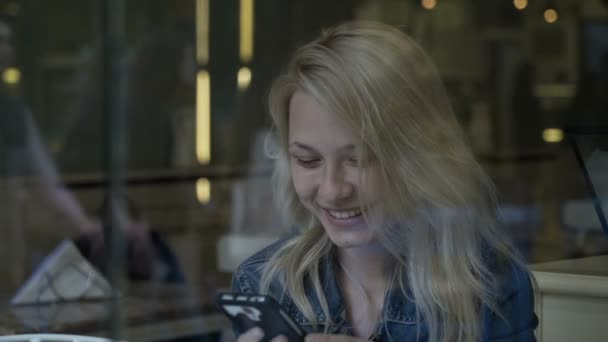 Chica feliz charlando con el teléfono inteligente durante el lugar de reunión en el bar cafetería — Vídeos de Stock