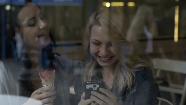 可爱的年轻女孩坐在酒吧里聊天，使用智能手机检查社会媒体和玩游戏的朋友 — 图库视频影像