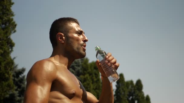 Movimento lento del body builder acqua potabile dalla bottiglia di plastica — Video Stock