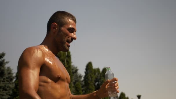 Nasser Bodybuilder mit Wasser über dem Körper an heißen Sommertagen — Stockvideo