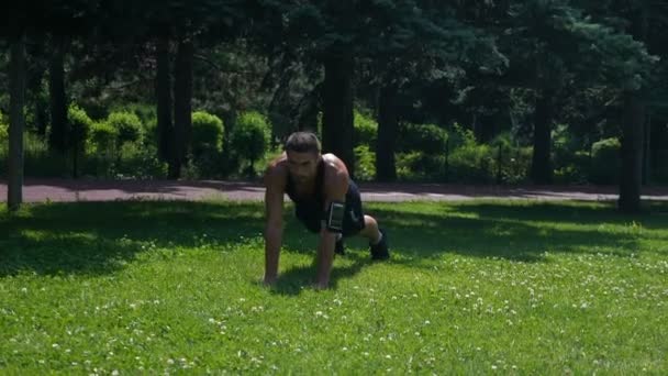 Hombre atlético en forma fuerte entrenando en la hierba en el parque — Vídeos de Stock