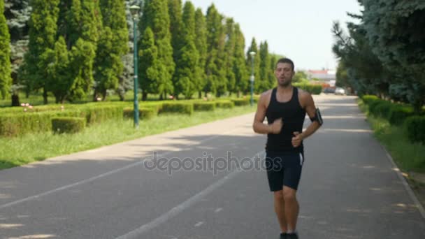 Homem atlético correndo no parque e verificando aplicativo rastreador de fitness de telefone inteligente — Vídeo de Stock