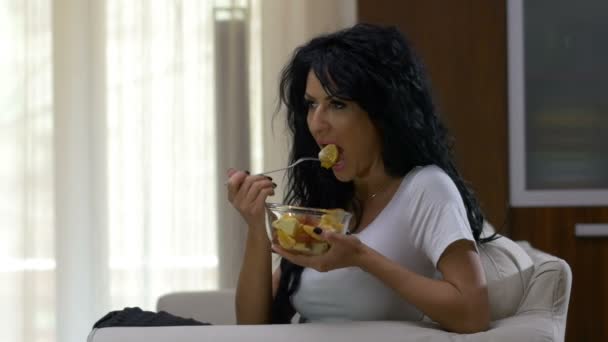 Gelukkige vrouw op een laag calorie groente dieet levensstijl vergadering op Bank en gezond eten haar fruitsalade — Stockvideo