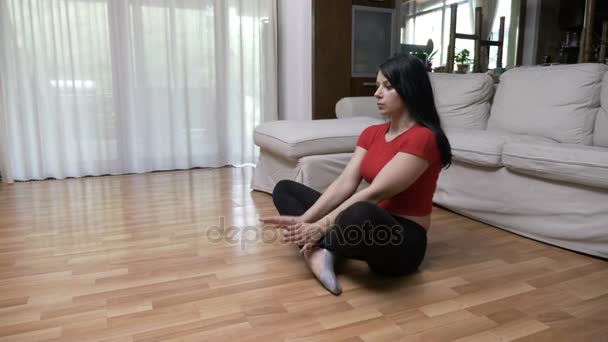 Молодая женщина делает йогу дыхательные упражнения и медитирует в позе лотоса на полу дома — стоковое видео