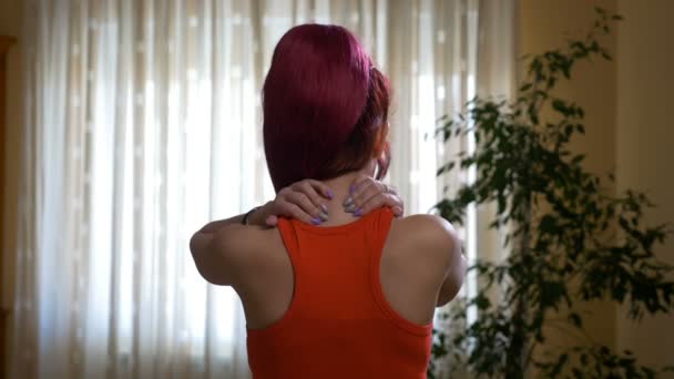 Молодая женщина с болью в шее хватается за голову — стоковое видео