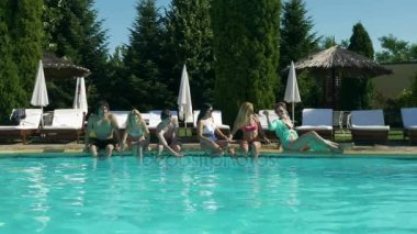 Güneşlenme ve havuzun yanında su ile oynayan insanlar