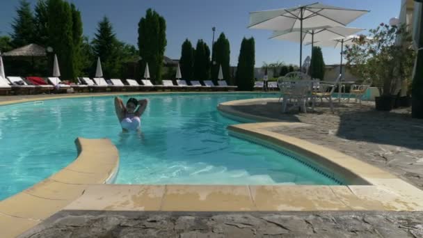 Jovem mulher sexy em maiô branco sai da piscina — Vídeo de Stock