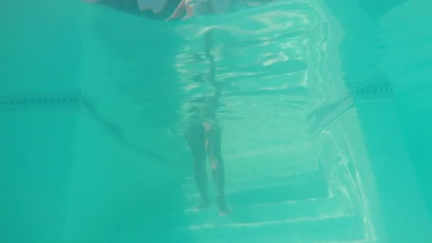 Стрілянина зсередини у воду з тілом жінки, що входить у басейн для плавання — стокове відео