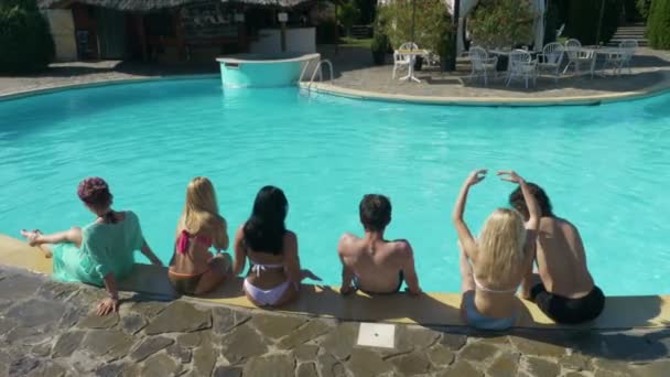 Grupp vänner sitta vid poolen i en privat villa väntar parten att starta — Stockvideo