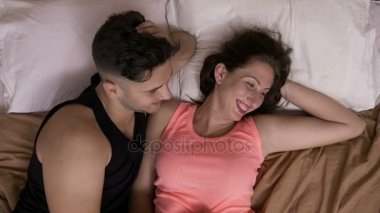 Genç çift sarılma ve yatakta onu onun şaka gıdıklıyor ve gülerek oturan rahat