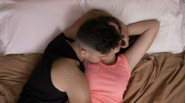 Genç adam yanında rahatlatıcı ve onu sevecen kız arkadaşı yatakta döşeme ile Çift
