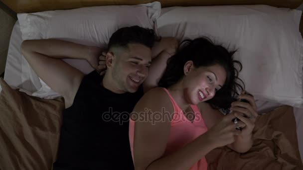 Felice coppia sposata guardando un video divertente sui social media su uno smartphone sul letto a casa — Video Stock