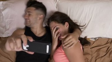 Kız ve erkek arkadaşı smartphone kullanarak Internet korku film izlerken yatakta rahat oturan