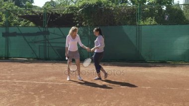 Genç kadın tenis dersleri alır ve tenis raketi tutun ve topa vurmak nasıl öğrenir