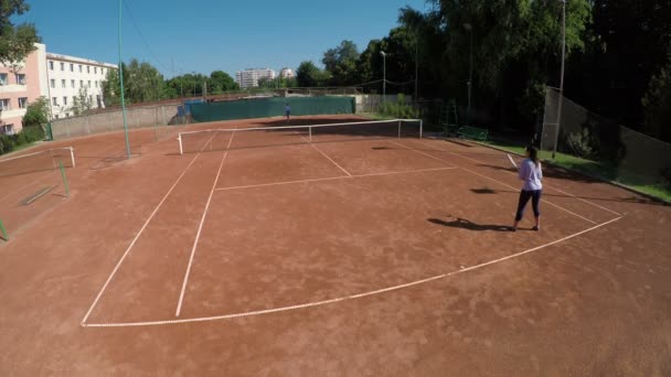 Dos mujeres juegan al tenis al aire libre en la arena de tenis — Vídeo de stock