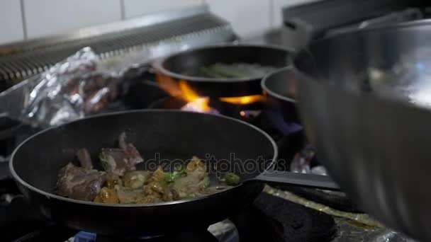 Молодой шеф-повар готовит мясо ягненка и экзотические овощи в роскошном ресторане на плите в кастрюле — стоковое видео