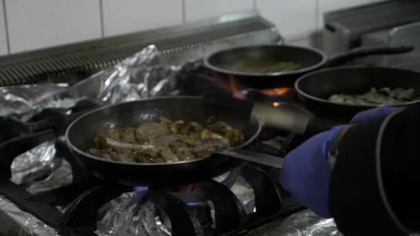 Крупный план плиты с кастрюлей и варкой шеф-повара добавляя оливковое масло и пылая смесь овощей и мяса — стоковое видео