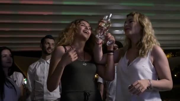 Deux jolies femmes trinquant et buvant du champagne et s'embrassant sur la piste de danse — Video