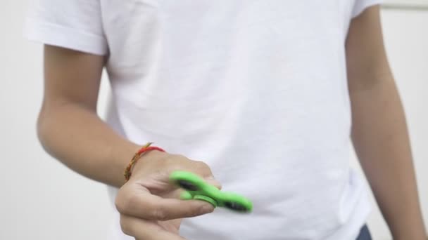 Movimiento lento del dispositivo de spinner fidget verde en la mano adolescente — Vídeos de Stock