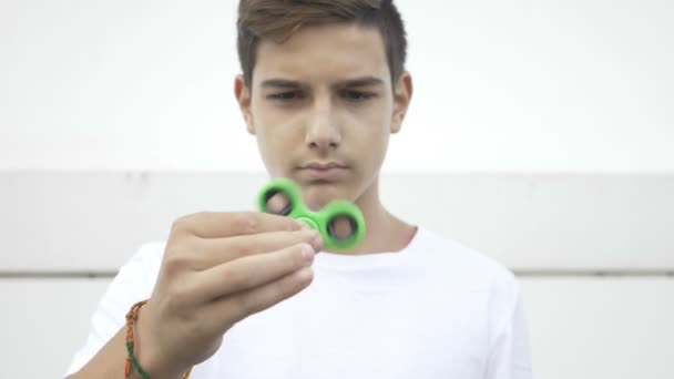 Garçon concentré tenant entre les doigts un jouet anti-stress de spinner de fidget roulant 