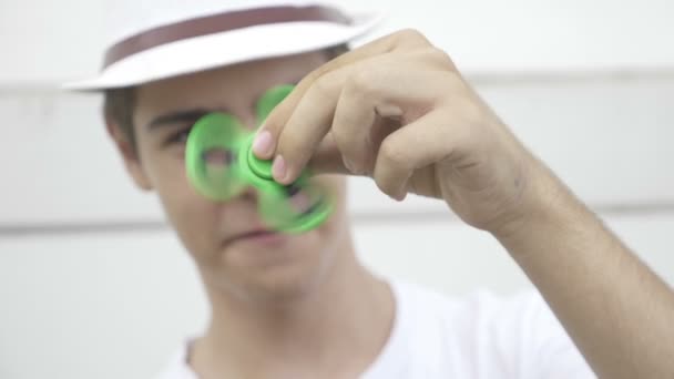 Playful teenage man having fun with hand fidget spinner outdoor — Stock Video