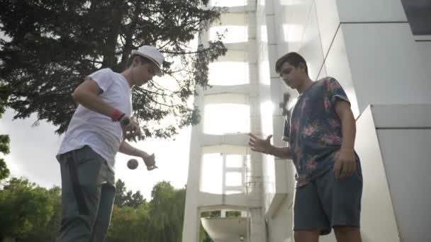 Dos adolescentes amigos entrenando y aprendiendo técnicas con juguetes kendama afuera — Vídeo de stock