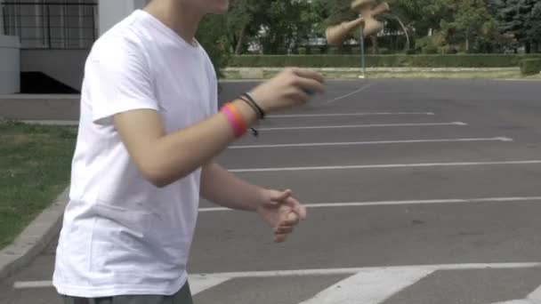 Cool niño aprendiendo el faro y saltando palo kendama se mueve fuera en el patio de la escuela — Vídeos de Stock