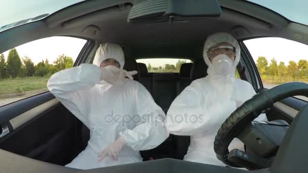 Jóvenes científicos divertidos sentados en el coche vestidos con ropa de materiales peligrosos bailando y sintiéndose energizados y celebrando el logro — Vídeo de stock