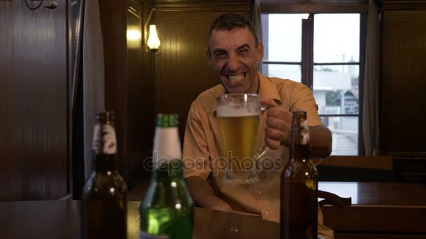 Hombre borracho riendo y bebiendo cerveza solo en un pub — Vídeos de Stock