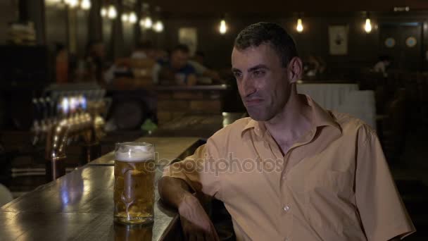 Ellendig depressieve man met een bier alleen aan de bar in een pub — Stockvideo