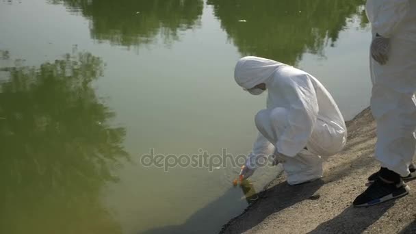 Equipe de técnicos Hazmat tomar amostra de água infectada em um parque e examiná-lo perto do lago contaminado — Vídeo de Stock