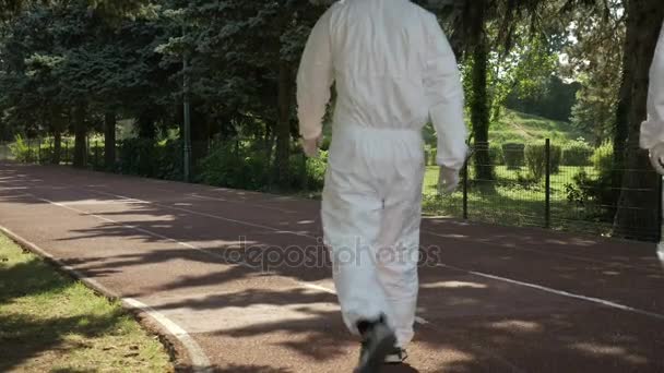 Hazmat technici team lopen op een een steegje in openbaar park naar verontreinigde gebied — Stockvideo