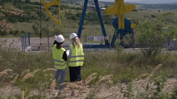 Joven empleada ingeniera discutiendo sobre proyecto de desarrollo industria petrolera comprobando instalación bomba de aceite capacidad — Vídeo de stock