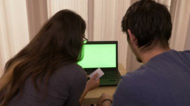 Güzel genç kadın evde Online vergi ödeme bankacılık yeşil ekran ve onun erkek arkadaşı alır heyecan ile bir dizüstü bilgisayar kullanarak